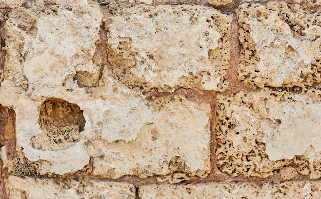 Fondo del muro de piedra del castillo realizado con piedras de diferentes formas, tamaños y texturas.