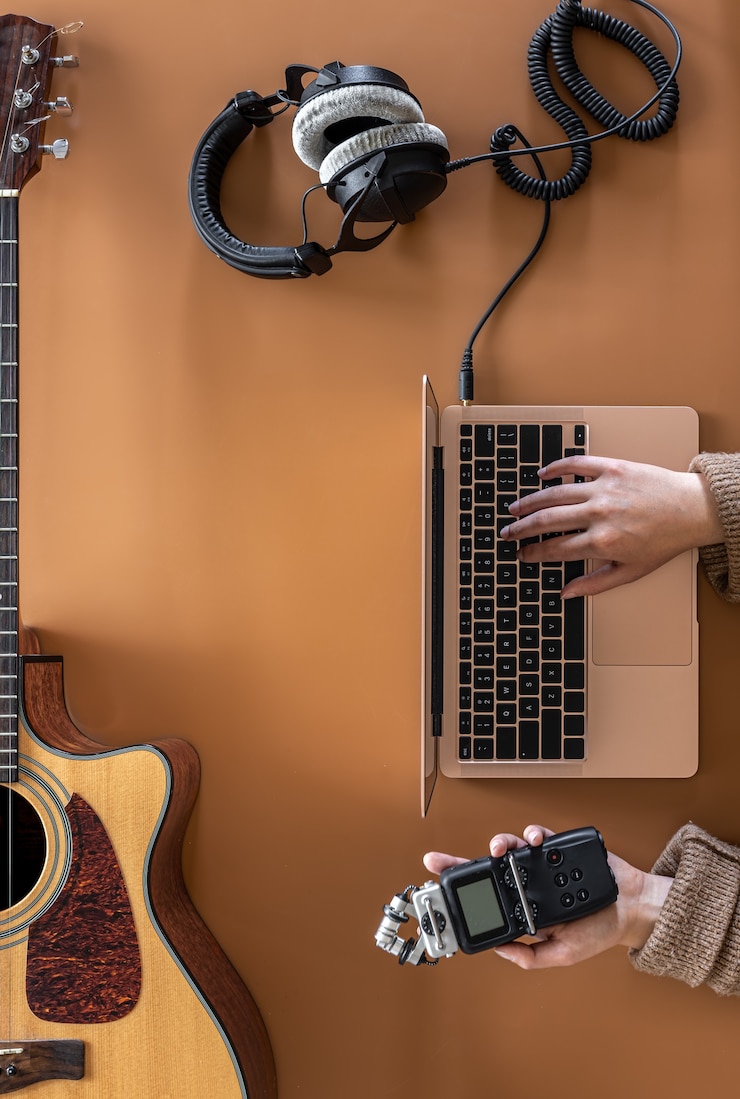 Foto fondo de música con auriculares, portátil y guitarra, plano laical.