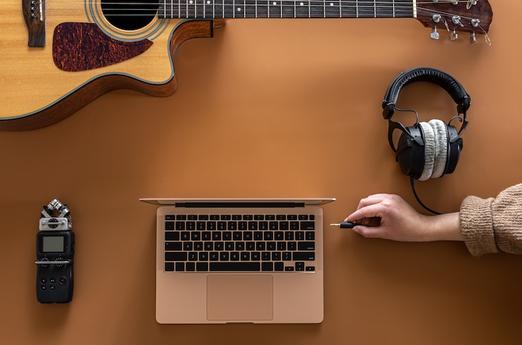 Foto fondo musical con auriculares, portátil y guitarra plana.