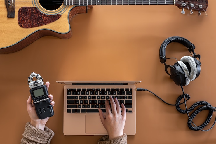 Foto fondo musical con auriculares, portátil y guitarra plana.
