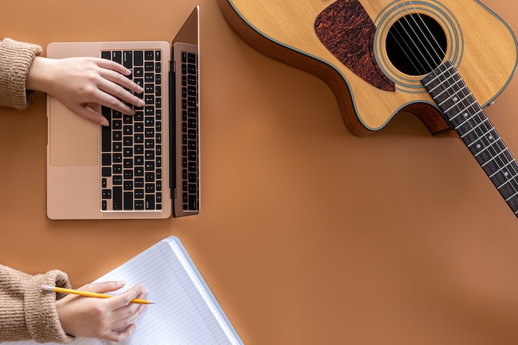 Foto fondo musical con portátil de guitarra acústica y vista superior de manos femeninas