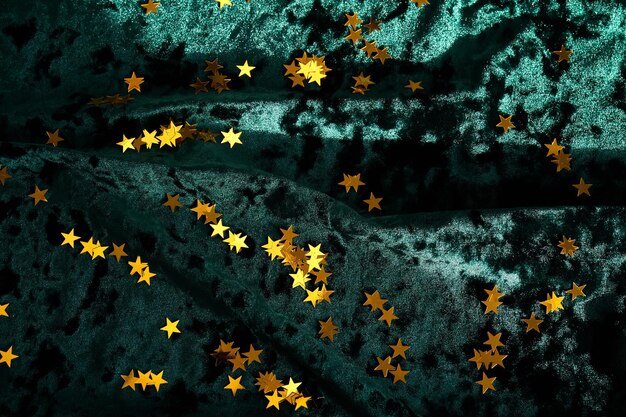 Fondo de Navidad abstracto con estrellas doradas en un fondo de terciopelo verde