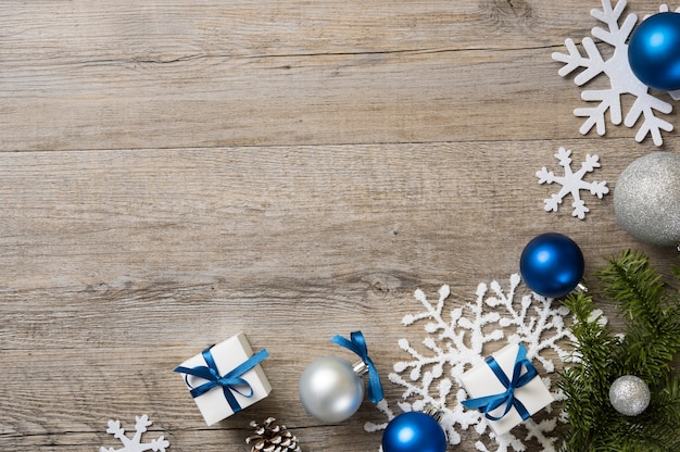 Fondo de Navidad con adornos y cajas de regalo blancas con cinta azul en la mesa de madera.