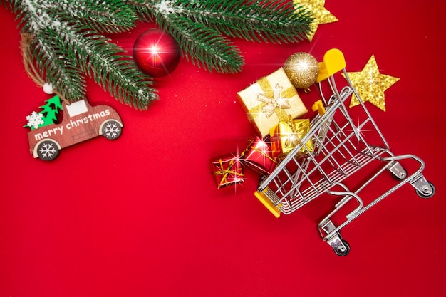 Fondo de navidad con adornos de carro de compras sobre fondo rojo espacio de copia