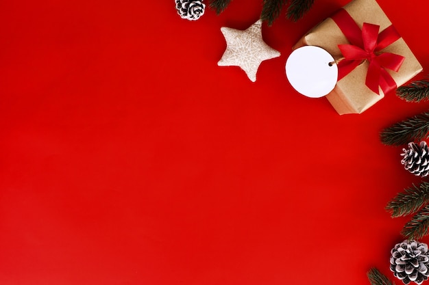 Fondo de Navidad y Año Nuevo - regalo de Navidad, hojas de abeto, cono de pino y estrellas sobre fondo rojo. Concepto de vacaciones. Diseño plano creativo, vista superior