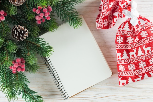 Fondo de Navidad con árbol de Navidad y tarjeta de felicitación de nota vacía sobre superficie de madera blanca.