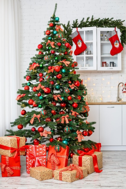 Fondo de Navidad: árbol verde decorado con bolas rojas y verdes, adornos navideños, guirnaldas amarillas. Año nuevo. Regalos debajo del árbol para las vacaciones.