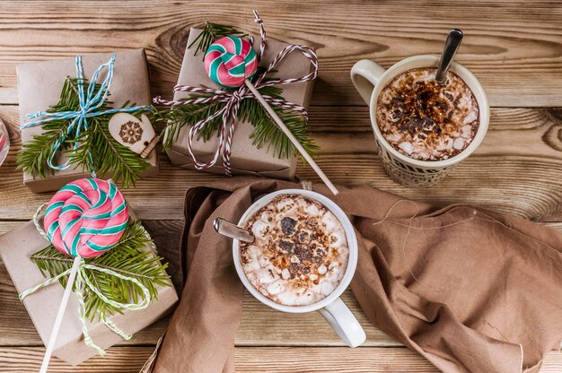 Fondo de navidad Café con malvaviscos, regalos, ramas y piruletas en madera