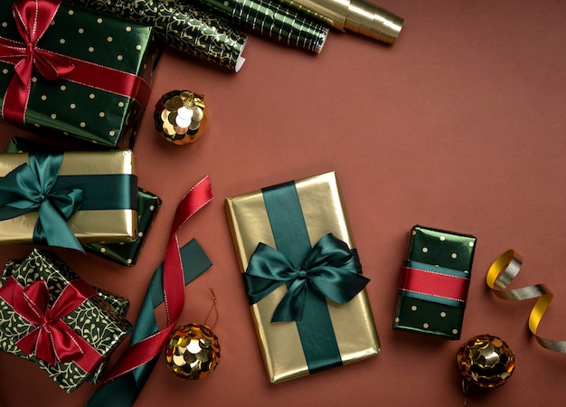 Fondo de Navidad con cajas de regalo, cintas de raso y rollos de papel de regalo sobre fondo marrón