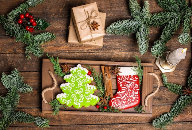 Fondo de navidad con cajas de regalo pan de jengibre en bandeja de madera y vela vintage