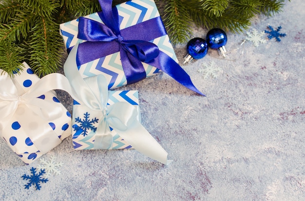 Fondo de navidad Cajas de regalo y ramas de abeto con decoración en color azul.