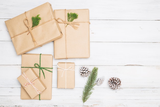 Fondo de Navidad con cajas de regalo de regalo hecho a mano y decoración rústica en tablero de madera blanca. Composición plana creativa y composición de vista superior con diseño de frontera y espacio de copia.