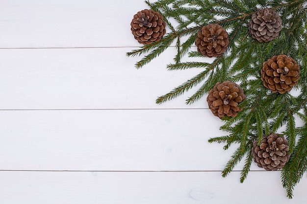 Fondo de Navidad con conos y ramas de abeto sobre tablas de madera blancas