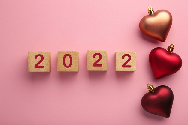 Fondo de Navidad con corazones rojos y números 2022. Concepto de año nuevo en rosa. Vista superior