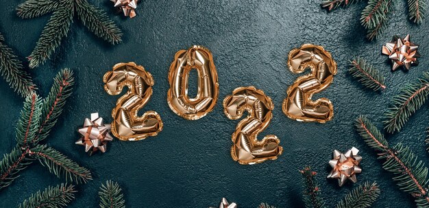 Fondo de Navidad creativo con ramas de abeto verde y decoración de globos de lámina dorada de texto 2022.