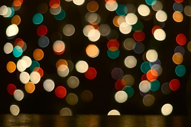 El fondo de Navidad es una mesa oscura y luces multicolores borrosas en el fondo