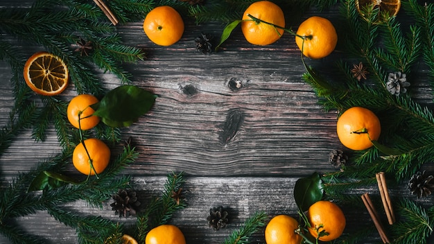 Fondo de Navidad con mandarinas y ramas de abeto, piñas, canela, anís estrellado