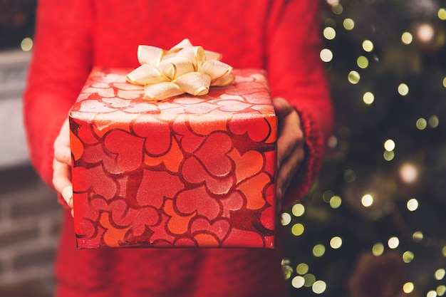 Fondo de Navidad Manos de mujer sosteniendo caja de regalo decorada de Navidad o año nuevo