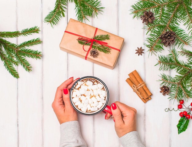 Fondo de navidad con manos sosteniendo taza con chocolate caliente o café con malvavisco