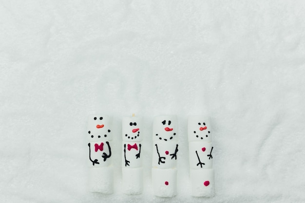 Fondo de Navidad con muñeco de nieve de malvavisco en nieve falsa. Foto de alta calidad