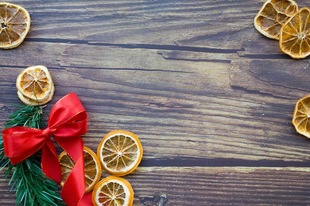 Fondo de Navidad de naranjas secas, ramita de pino y lazo rojo sobre una mesa de madera