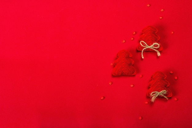 Fondo de Navidad o año nuevo. Abeto de ganchillo hecho a mano, dulces copos de nieve sobre fondo rojo áspero. Diseño monocromático minimalista, plano