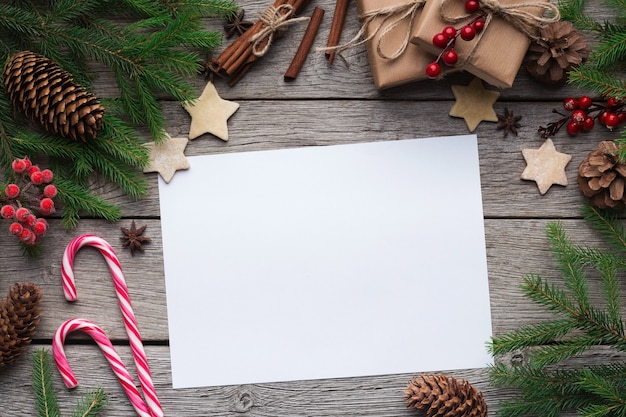 Fondo de Navidad, papel blanco en blanco en marco con abeto y adornos navideños en tablero de madera rústica, vista superior, espacio de copia