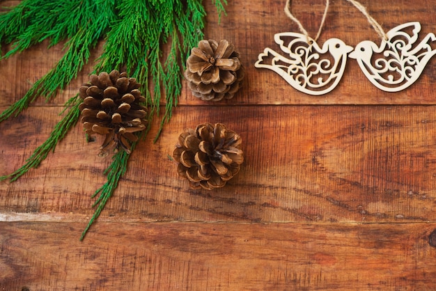 Fondo de Navidad. Ramas de abeto, regalo, piñas y figuras de pájaros de madera sobre un fondo de madera. Copia espacio