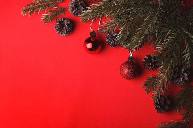 Un fondo de Navidad ramas de árboles de Navidad bolas de Navidad y conos sobre un fondo rojo.