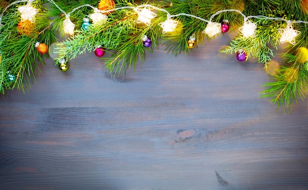 Fondo de navidad con ramas de pino y guirnalda de luces navideñas de madera