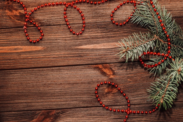 Fondo de Navidad con ramita de abeto y juguetes rojos sobre tablas de madera.