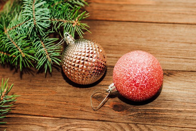 Fondo de Navidad con ramita de abeto y juguetes rojos sobre tablas de madera.