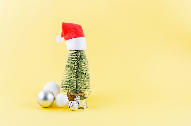 Fondo de Navidad. Árbol de Navidad y caja de regalo negra con cinta dorada sobre fondo amarillo.