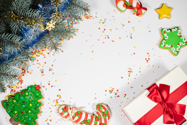 Fondo de Navidad con regalo y pan de jengibre. Tarjeta de humor de vacaciones. Vista superior, espacio de copia. Tradiciones familiares, bricolaje, concepto de celebración. Fondo festivo con galletas de jengibre caseras.