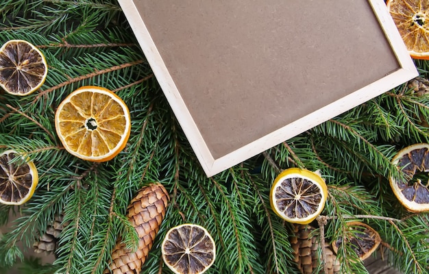 Fondo de Navidad con rodajas de naranja secas y tablero enmarcado vacío en ramas de abeto espinoso verde. Elemento de diseño festivo de año nuevo.
