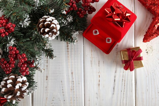 Fondo de Navidad. Tablas de madera blanca con ramas de abeto, piñas, caja de regalo roja.