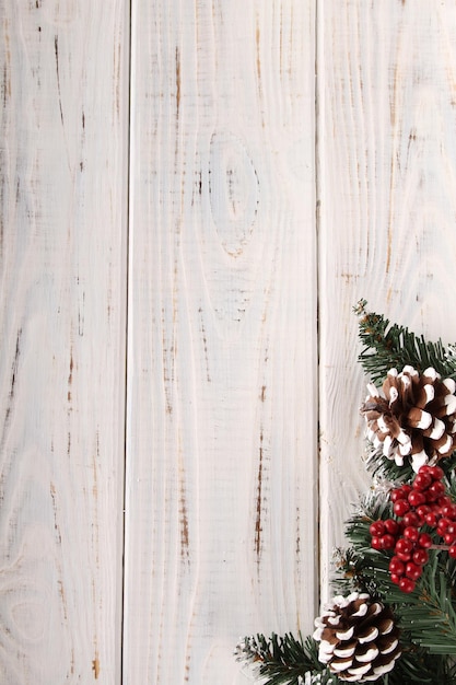 Fondo de Navidad. Tablones de madera blanca con ramas de abeto, piñas, nieve y frutos rojos