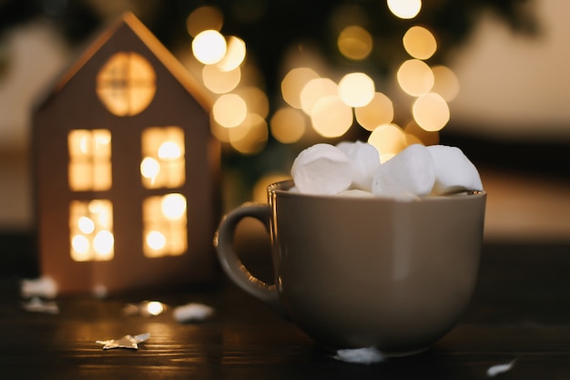 Fondo de Navidad con una taza de café con malvaviscos por luces bokeh