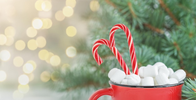 Fondo navideño con bebida navideña con malvaviscos y bastones de caramelo