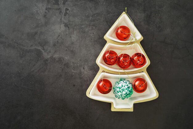 Foto fondo navideño plato en forma de árbol de navidad con adornos de bolas en la mesa