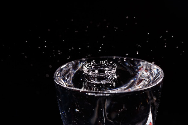 El fondo negro es un vaso en el que cae una gota de agua. Salpicaduras de agua sobre el vidrio