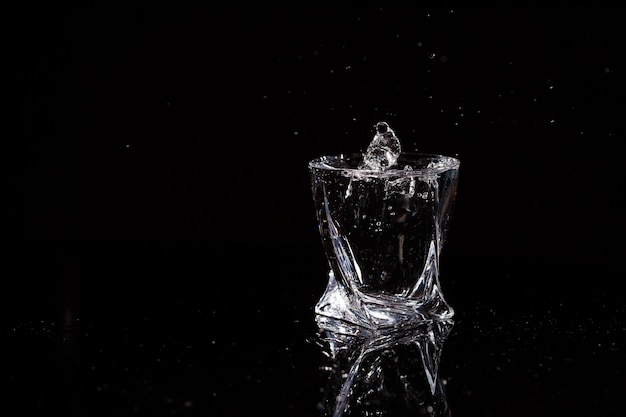 El fondo negro es un vaso en el que cae una gota de agua. Salpicaduras de agua sobre el vidrio