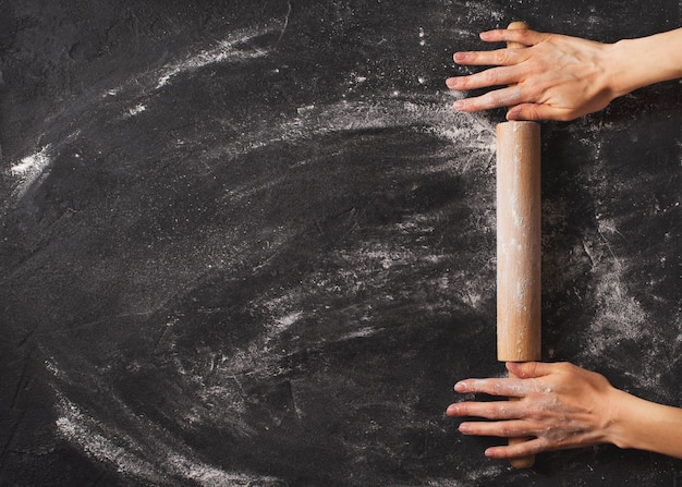 Fondo negro de panadería con rollo y manos femeninas planas