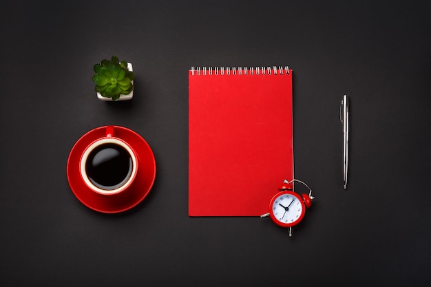 Fondo negro rojo taza de café bloc de notas despertador flor espacio vacío escritorio