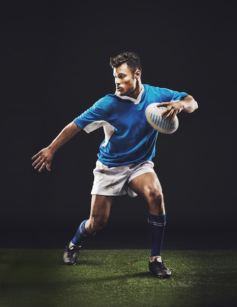 Fondo negro de rugby y atleta hombre corriendo en un estudio oscuro mientras entrena deportes de bienestar y fitness Ejercicio de ejercicio y carrera profesional de hombre o jugador deportivo en hierba