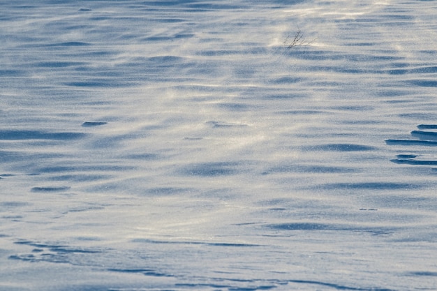 Fondo nevado, superficie nevada de la tierra después de una tormenta de nieve en la mañana a la luz del sol con distintas capas de nieve