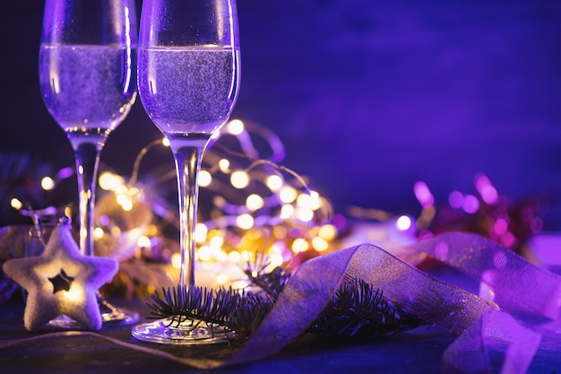 Fondo de noche de Navidad de colores brillantes de neón con dos copas de champán y espacio de copia