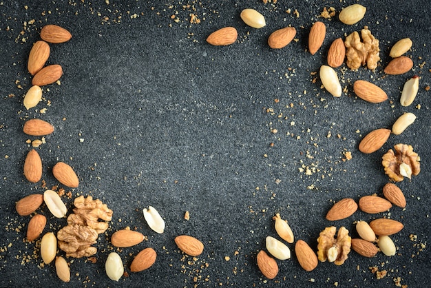 Fondo de nueces de almendras, cacahuetes y nueces con migas sobre fondo negro.