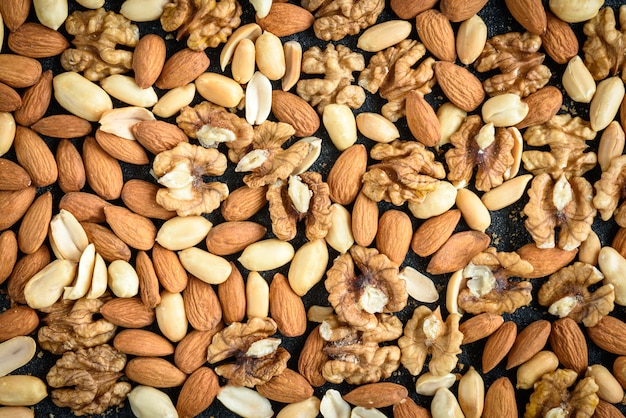 Fondo de nueces de almendras, cacahuetes y nueces con migas sobre fondo negro.