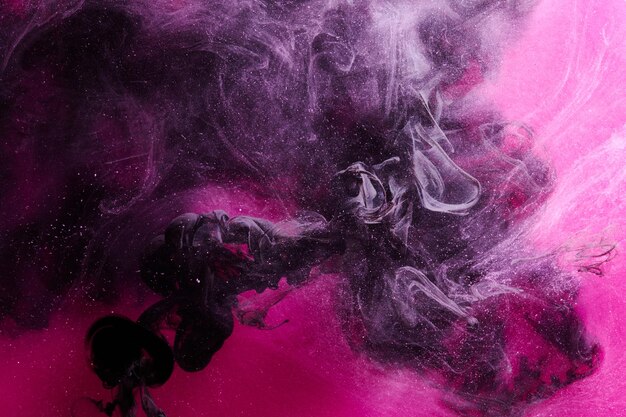 Fondo oceánico abstracto rosa oscuro y negro Salpicaduras de gotas y olas de pintura bajo nubes de humo en movimiento